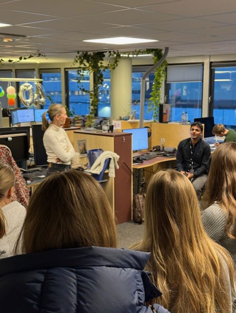 en person som står foran en gruppe mennesker som sitter ved pulter