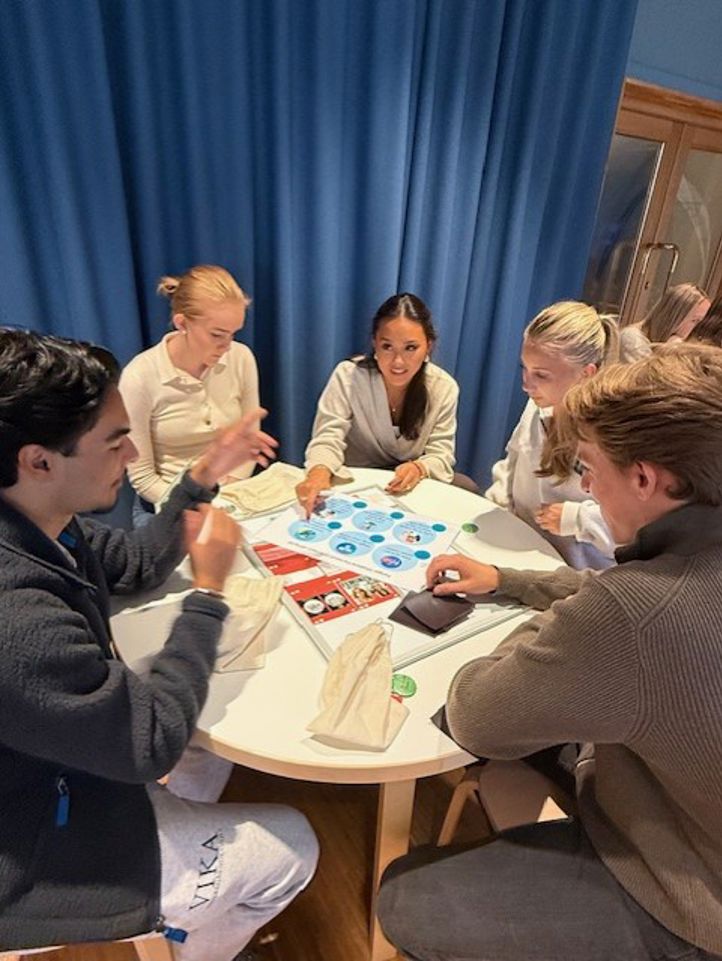 en gruppe mennesker som sitter rundt et bord og spiller et brettspill