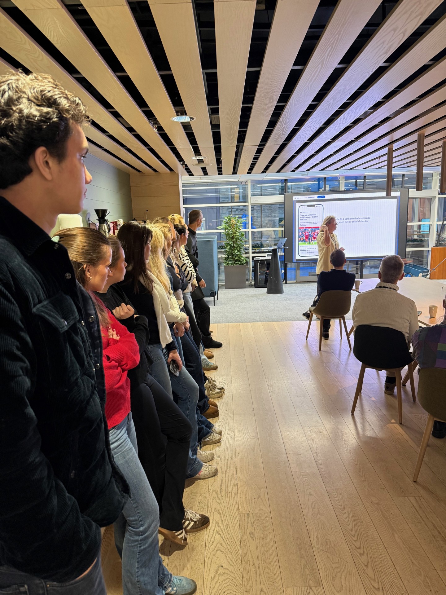 en gruppe mennesker som sitter i et rom og ser på en skjerm