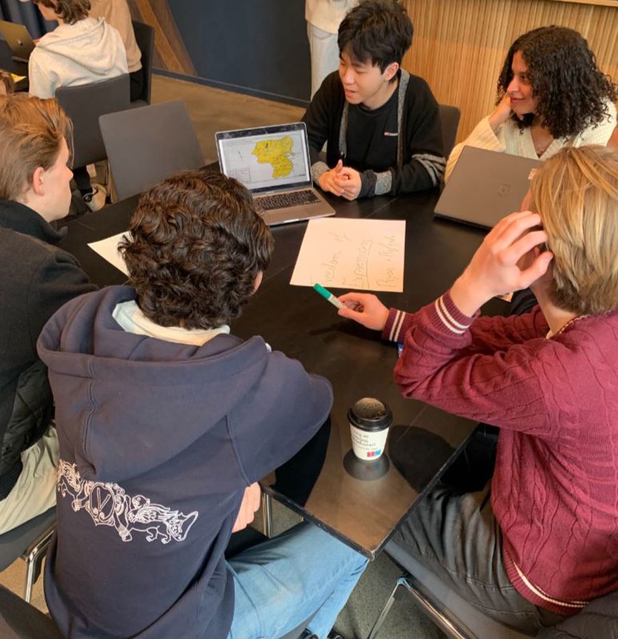 En gruppe mennesker som sitter rundt et bord med bærbare datamaskiner