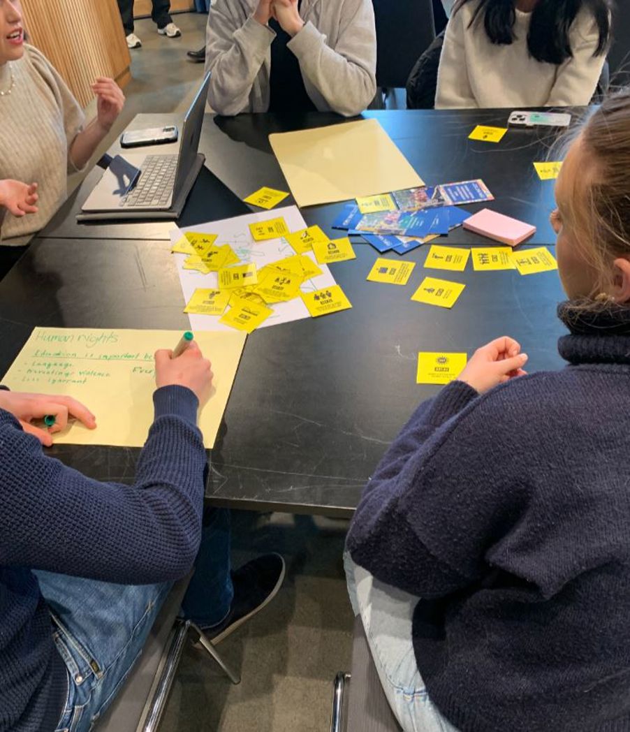 en gruppe mennesker som sitter ved et bord med gult papir på